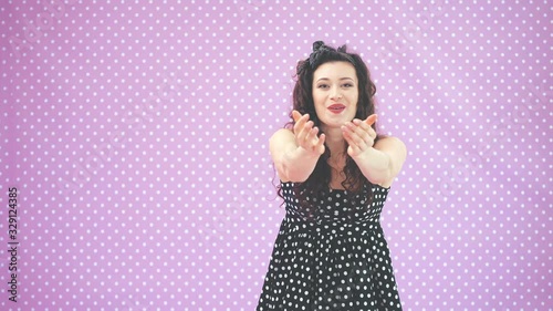 Funny curly girl in cute polka-dot dress is cathing some flying things from the air. photo