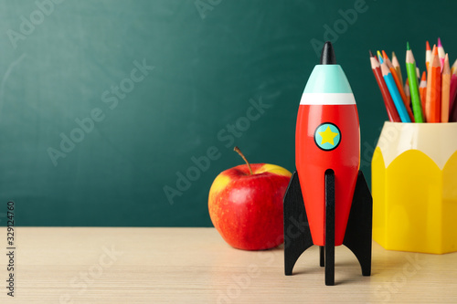 Bright toy rocket and school supplies on wooden desk. Space for text © New Africa