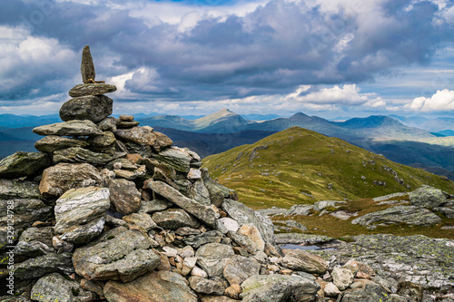 Tableau sur toile Cairn marking the peak of Ben Vorlich with the hills of the Scottish Highlands in the background on a summer day