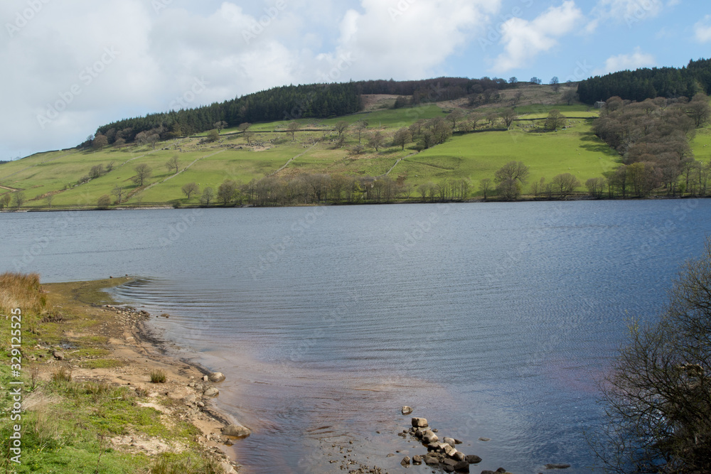 Tranquil water with hilly pastures and woodland in the background at Gouthwaite Reservoir,Nidderdale,which is situated between the small villages of Wath and Ramsgill,North Yorkshire.