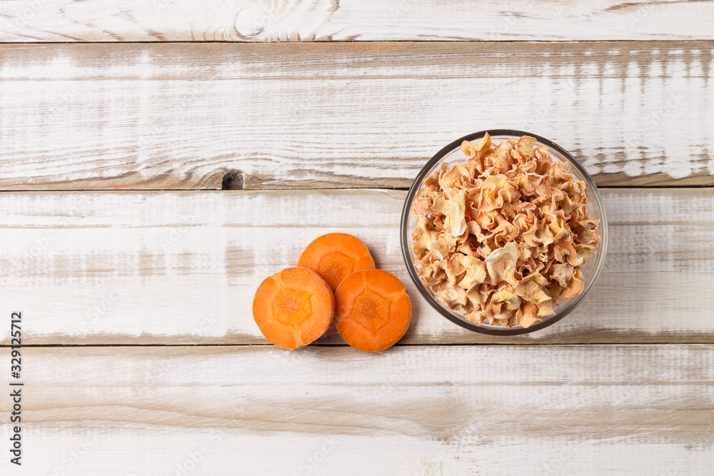 Carrot chips from juicy slices in a bowl on a wooden table. Flat lay. Image contains copy space. Carrot chips from juicy slices in a bowl on a wooden table. Flat lay. Image contains copy space.