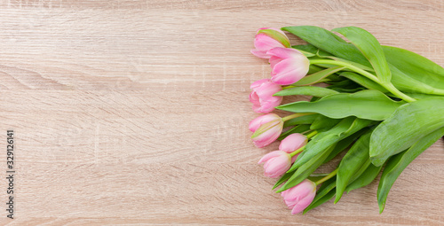 Rosarote Tulpen auf einem hellen Holztisch