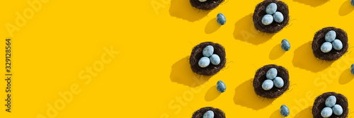 Blue textured colored Easter eggs and bird nest on a bright yellow holiday background backdrop. Spring holiday concept. Copyspace. Flat lay. Top view. Hard light. Long shadow.