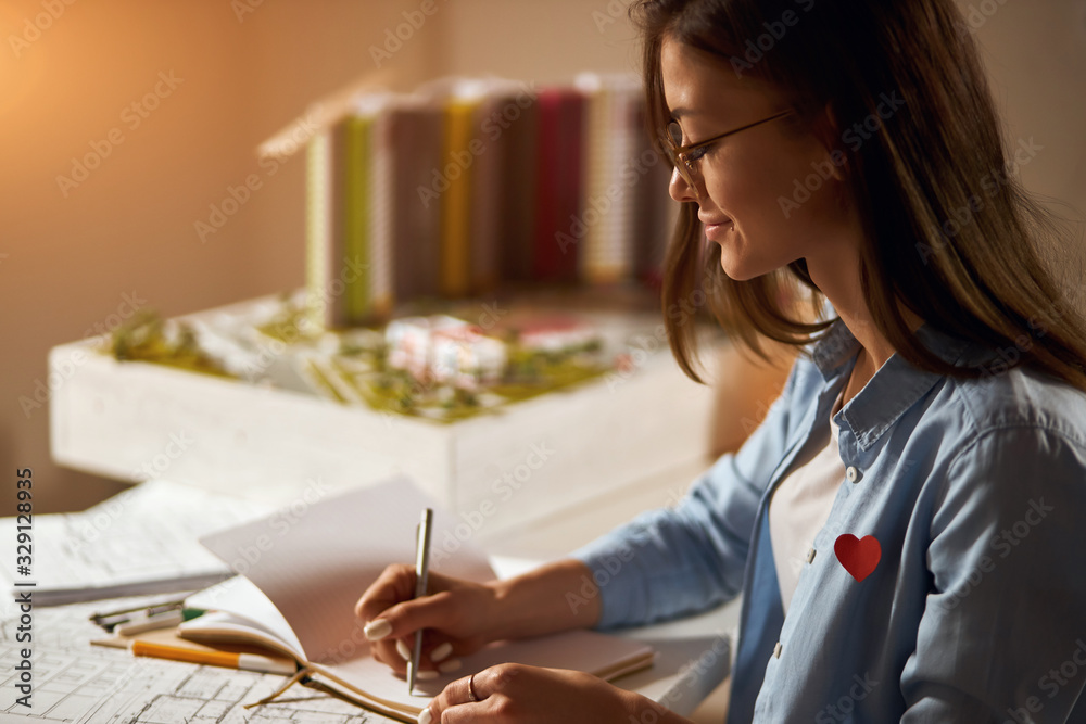 concentrated businesswoman working on blueprint in office, close up side view photo. girl writing her ideas, planning her working day in the office. layout in the blurred background of the photo concentrated businesswoman working on blueprint in office, close up side view photo. girl writing her ideas, planning her working day in the office. layout in the blurred background of the photo