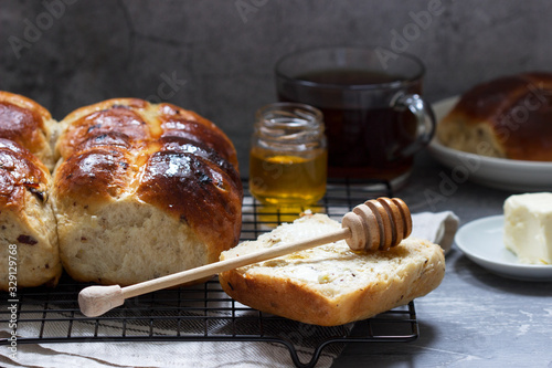 Traditional hot cross buns with honey and butter on a concrete background.