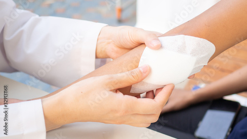 Doctor is using cotton dressing a wound at a women arm.