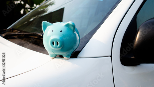 piggy bank on a car, saving money for new car.