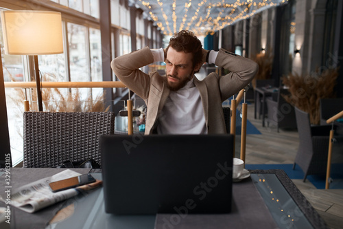 frustrated unhappy sad man isn't satisfied with company work, guy solving problems, man is angry as his laptos has broken, negative feeling and eemotion, man having headache photo