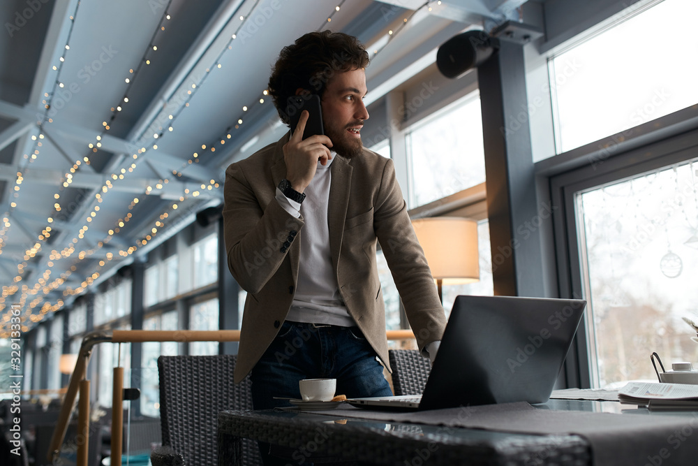 pleasant smart manager talking with colleagues, partners with smart phone, looking aside, at the window. pleasant smart manager talking with colleagues, partners with smart phone, looking aside, at the window.