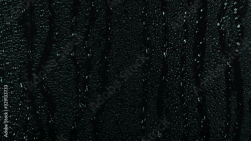 Rain water droplets trickling down the window pane at night