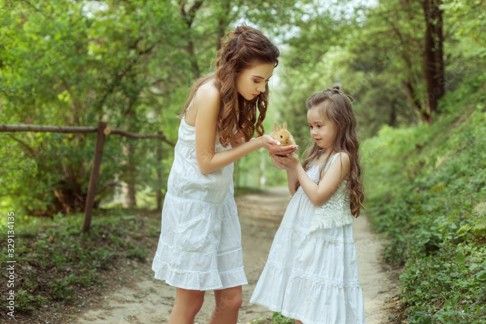 Young mother and daughter with a small rabbit. Young mother and daughter with a small rabbit.