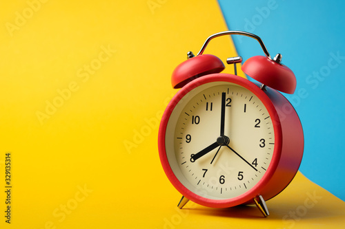 Red vinatge alarm clock show 8 o'clock with yellow and blue background.