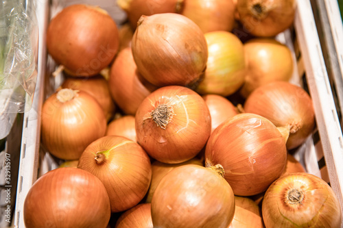 Pile of fresh onions in wooden box for sales in a local market or supermarket	