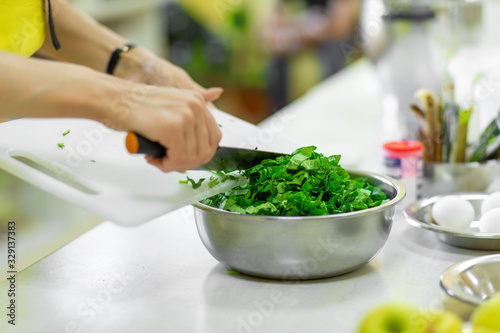 Cook in the kitchen cuts greens close up