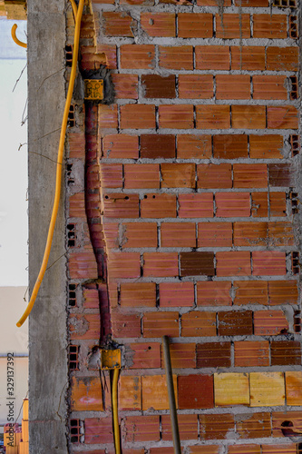 Construção de alvenaria. Coluna de concreto, tijolo baiano e conduíte elétrico	