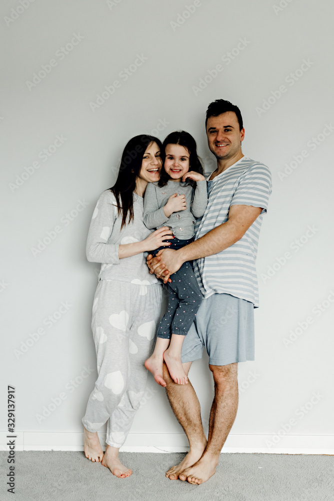 portrait of a happy family in the morning,family in pajamas,family photo,happy young family posing in pajamas at camera,dad mom and daughter take a photo as a keepsake portrait of a happy family in the morning,family in pajamas,family photo,happy young family posing in pajamas at camera,dad mom and daughter take a photo as a keepsake