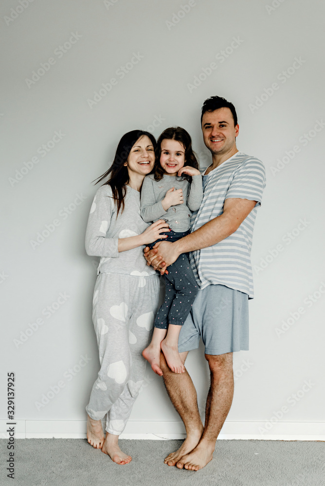 portrait of a happy family in the morning,family in pajamas,family photo,happy young family posing in pajamas at camera,dad mom and daughter take a photo as a keepsake portrait of a happy family in the morning,family in pajamas,family photo,happy young family posing in pajamas at camera,dad mom and daughter take a photo as a keepsake