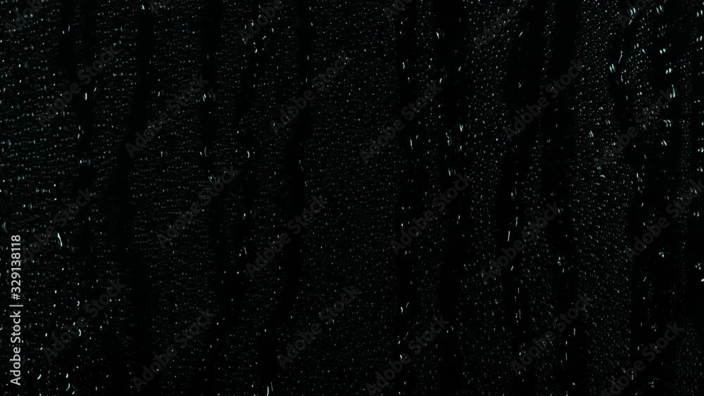 Rain water droplets slowly trickling down the window pane at night