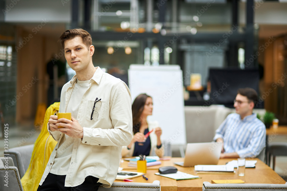 handsome man leaning on the desk and looking at the camera. close up photo. copy space. blurred background handsome man leaning on the desk and looking at the camera. close up photo. copy space. blurred background