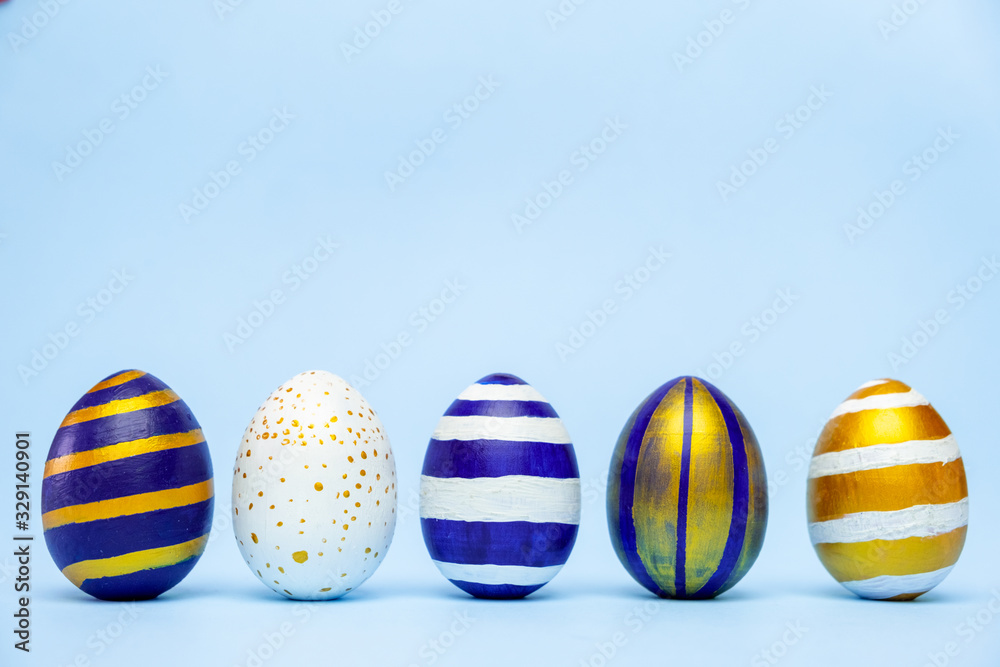 Five easter trendy colored classic blue and golden decorated eggs striped pattern on blue. Happy Easter card with copy space for text. Minimal style. Five easter trendy colored classic blue and golden decorated eggs striped pattern on blue. Happy Easter card with copy space for text. Minimal style.