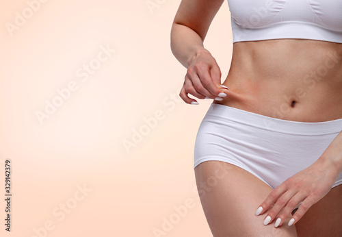 Woman pinches fat on her belly, closeup shot
