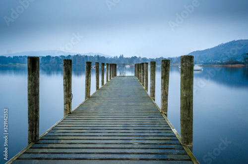 An evening view of one of the many jetties lining the shore of Lake Windermere showing a calm and misty water, 