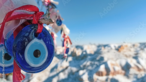 Evil eye charms hang on the tree with snow covered fairy chimneys landscape in Cappadocia, Turkey. photo