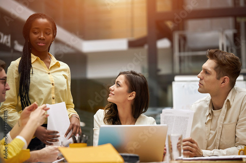 Quadro em tela afro woman in stylish yellow shirt bringing important documents to her co-worker