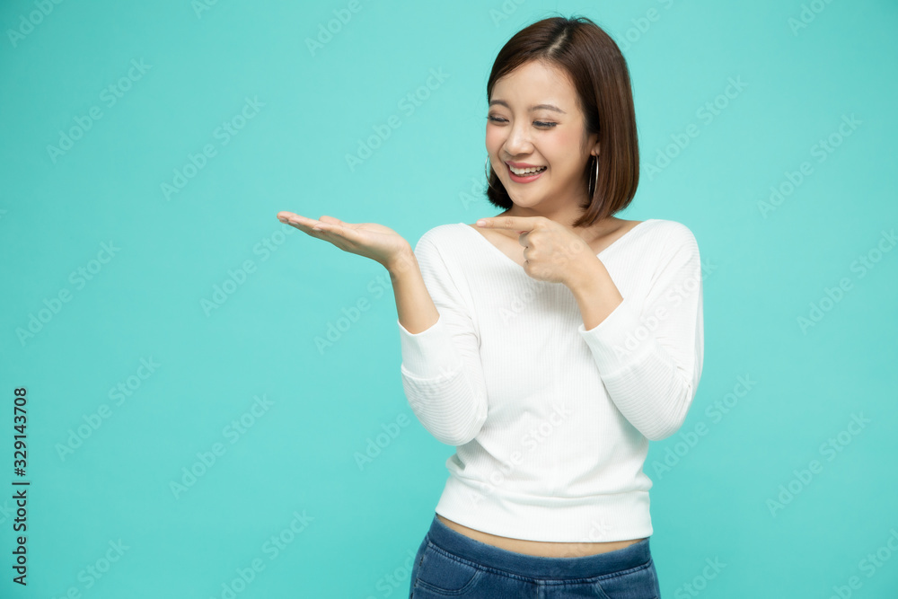Young elegant Asian woman smiling and presenting to empty copy space isolated on green background, Thai model Young elegant Asian woman smiling and presenting to empty copy space isolated on green background, Thai model