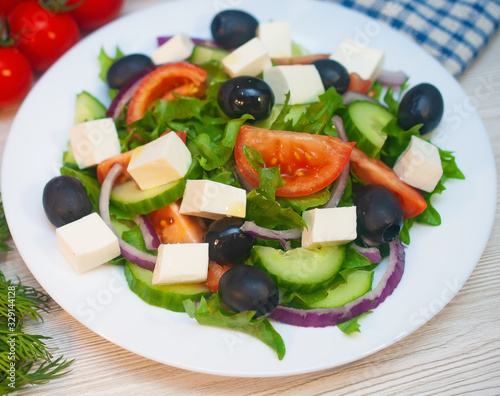 Greek salad with tomatoes, cucumbers and feta cheese with olives on the table