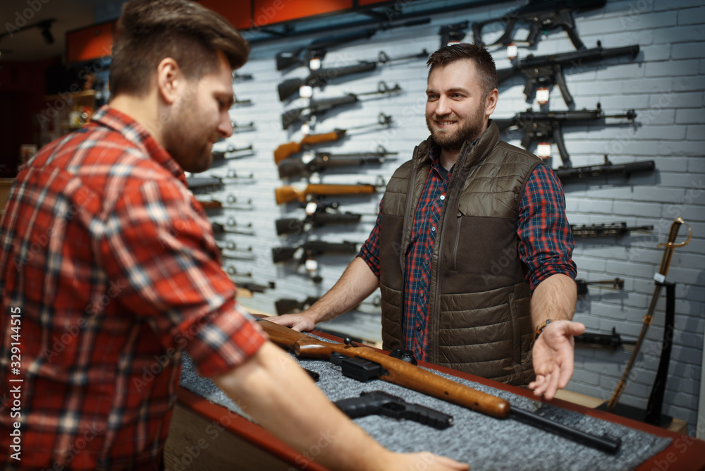 © Nomad_Soul - Man and owner choosing rifle in gun shop