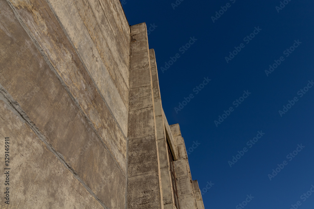 Concrete wall against the blue sky. Minimalism in modern architecture.
