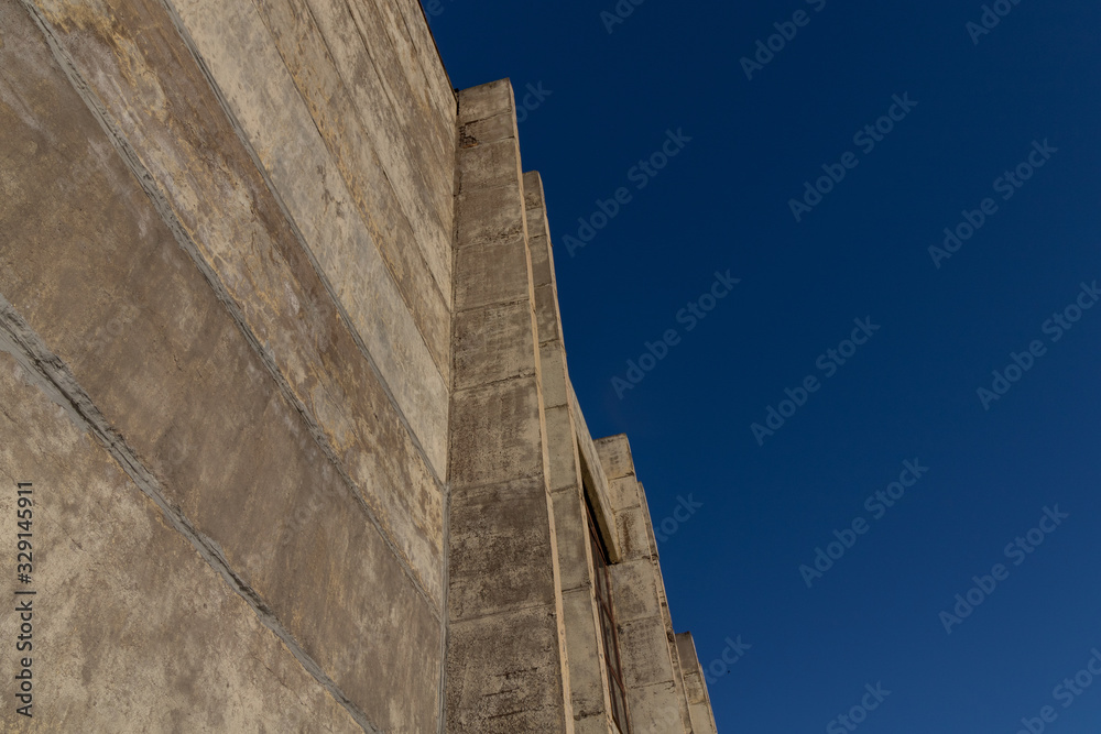 Concrete wall against the blue sky. Minimalism in modern architecture. Concrete wall against the blue sky. Minimalism in modern architecture.