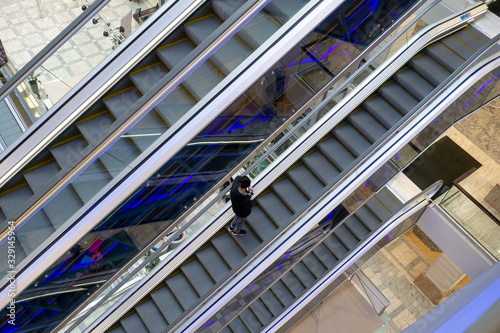 One customer on escalator stairs inside a giant modern shopping center. The concept of unprofitability of closing large shopping centers.