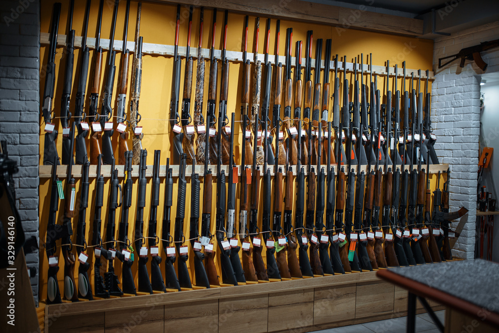 Rows of rifles on the wall, showcase in gun shop