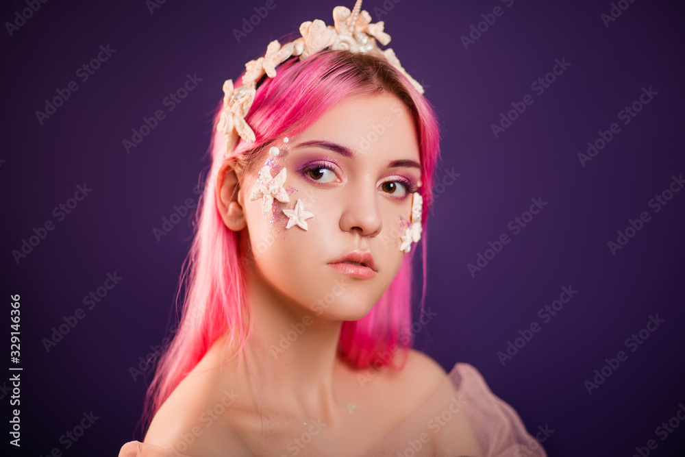 Close up portrait of a young beautiful girl with pink hair and professional make-up, sea princess with starfish and shells on her face and head. Halloween makeup. Close up portrait of a young beautiful girl with pink hair and professional make-up, sea princess with starfish and shells on her face and head. Halloween makeup.