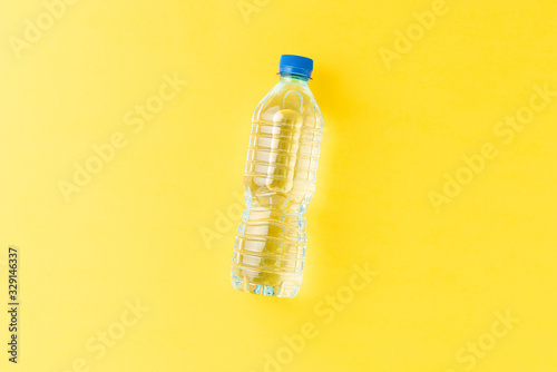 Bild auf Leinwand Overhead shot of mineral water in small plastic bottle on yellow background with