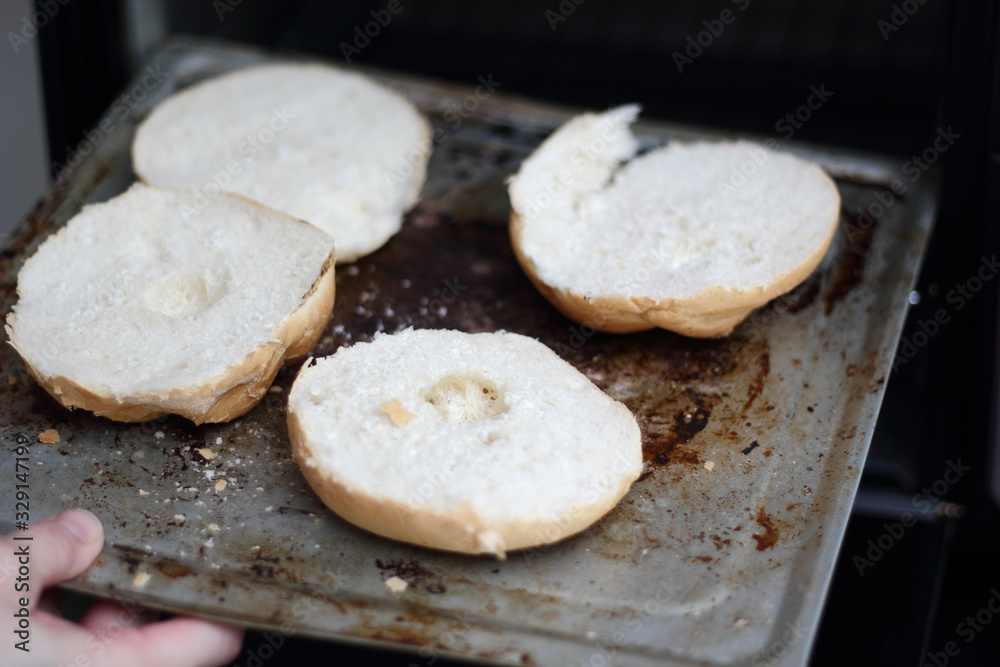 Place halves of bread rolls on tray into electric oven for toasting