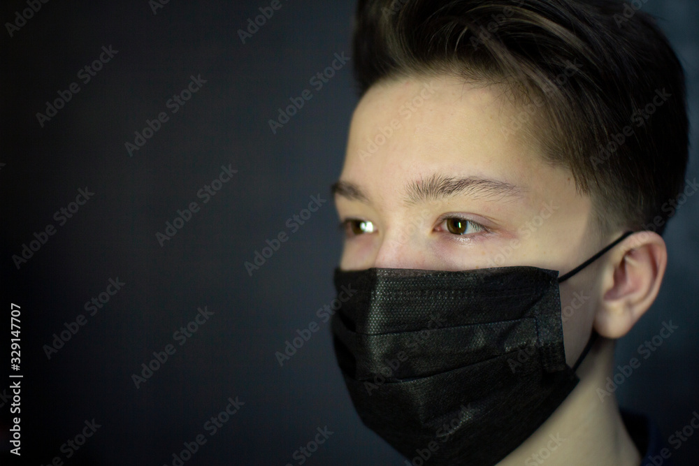 Portrait of a brown-eyed teenager in a black medical mask. Antivirus protection. Portrait of a brown-eyed teenager in a black medical mask. Antivirus protection.