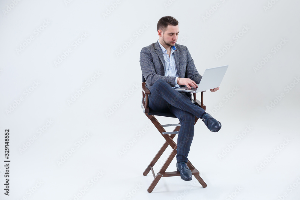 Male teacher director businessman sitting on a chair studying documents. He is looking at the laptop screen. New business project. Male teacher director businessman sitting on a chair studying documents. He is looking at the laptop screen. New business project.