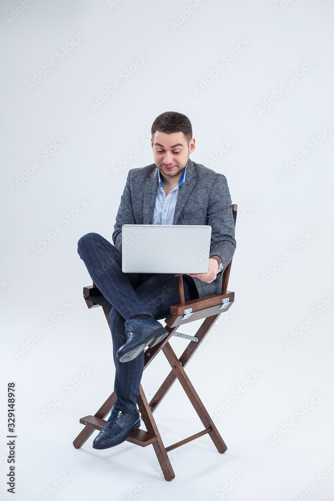 Male teacher director businessman sitting on a chair studying documents. He is looking at the laptop screen. New business project.