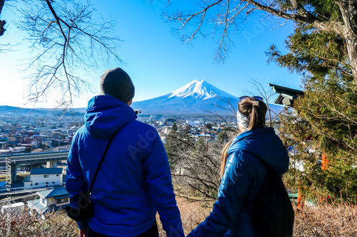 Photography A couple standing on the hilltop above Chureito Pagoda, Japan and admiring Mt Fuji in front of them