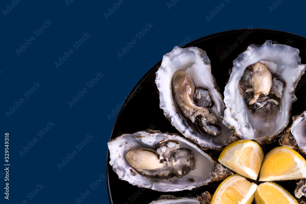 Oysters plate with lemon on blue background. Served table with oysters ...