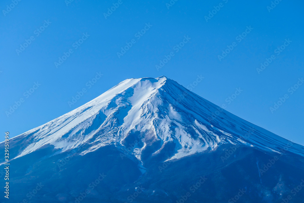 A distant, close up view on Mt Fuji in Japan on a clear, wintery day. Inaccessible slopes of the mountains are covered with a thick layer of snow. Holly mountain of Japan.