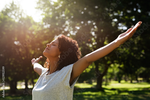 Woman standing in a park rasing her arms skyward photo