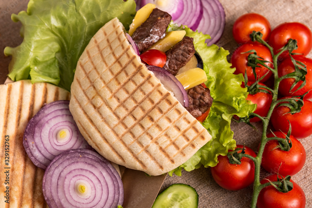 Pita doner kebab with green salad, potato free, tomatoes, cherry, cucumber and fried beef. Street food. Fast food. Doner kebab Pita doner kebab with green salad, potato free, tomatoes, cherry, cucumber and fried beef. Street food. Fast food. Doner kebab
