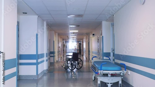 Medical wheelchair and gurney in the long hospital corridor.