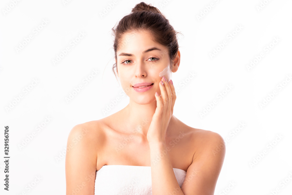 Young woman applying cream onto her face Young woman applying cream onto her face