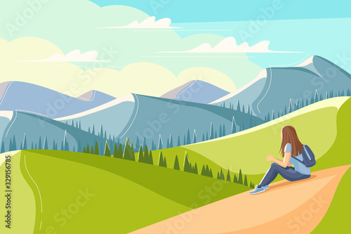 Young woman sits on the grass and looks at the mountains