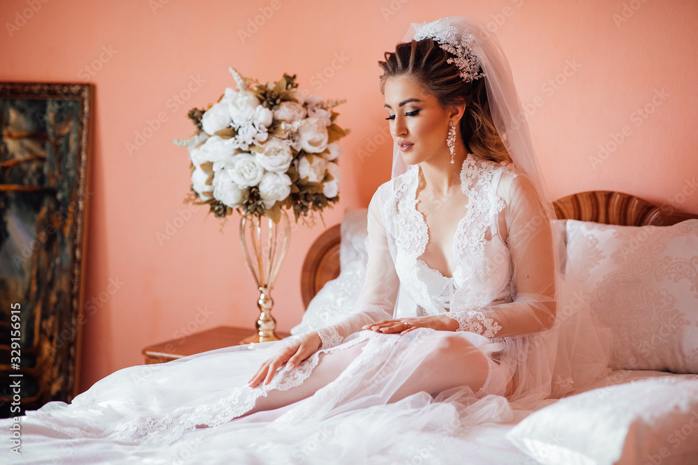Beautiful Bride with wedding makeup and hairstyle, Wedding dress. Gorgeous young bride at interior. Closeup portrait of young gorgeous bride. Wedding. Bride posing on bed in robe Beautiful Bride with wedding makeup and hairstyle, Wedding dress. Gorgeous young bride at interior. Closeup portrait of young gorgeous bride. Wedding. Bride posing on bed in robe